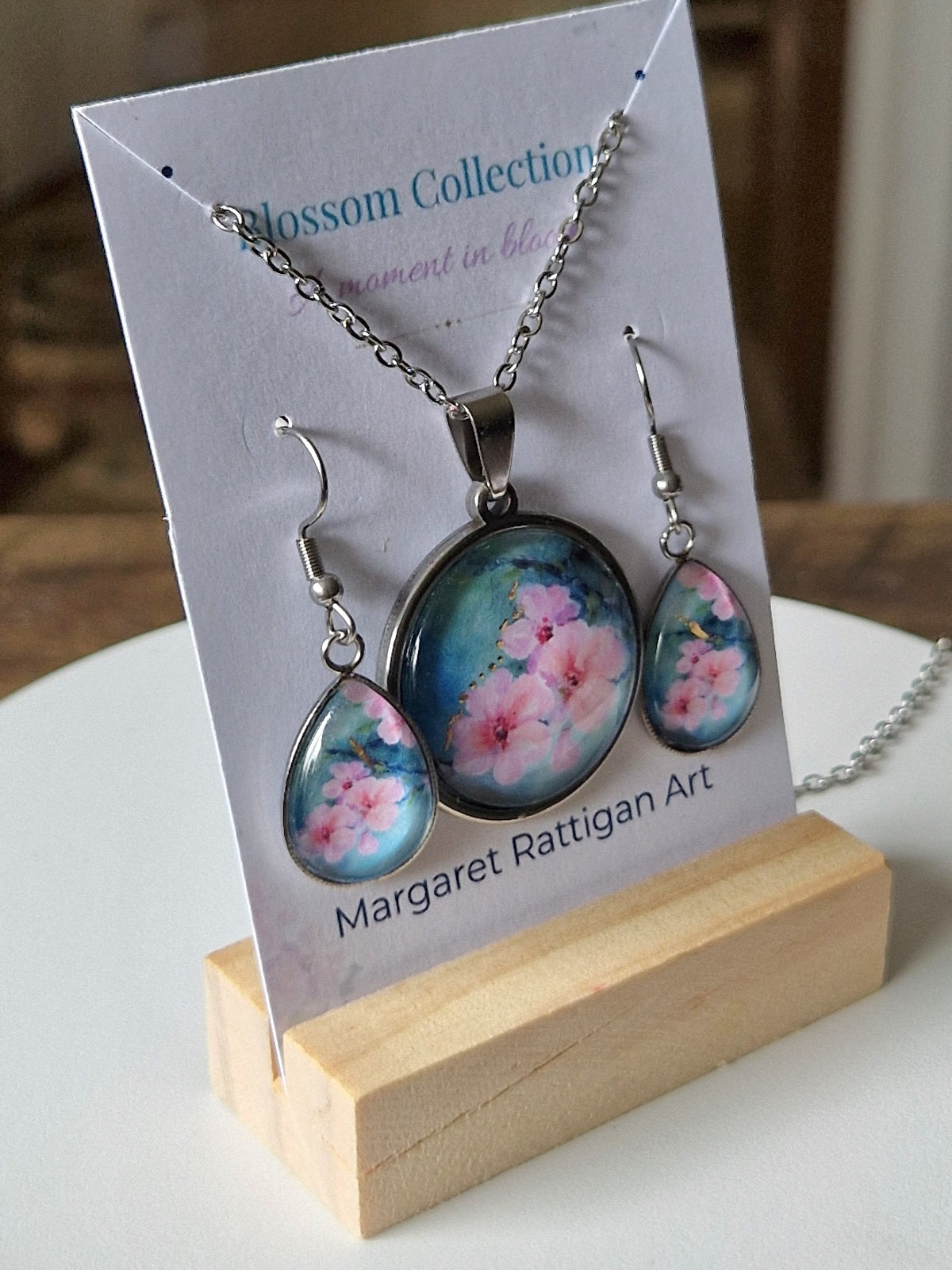 Jewelry set with floral pendant and earrings on a 'Blossom Collection' card.